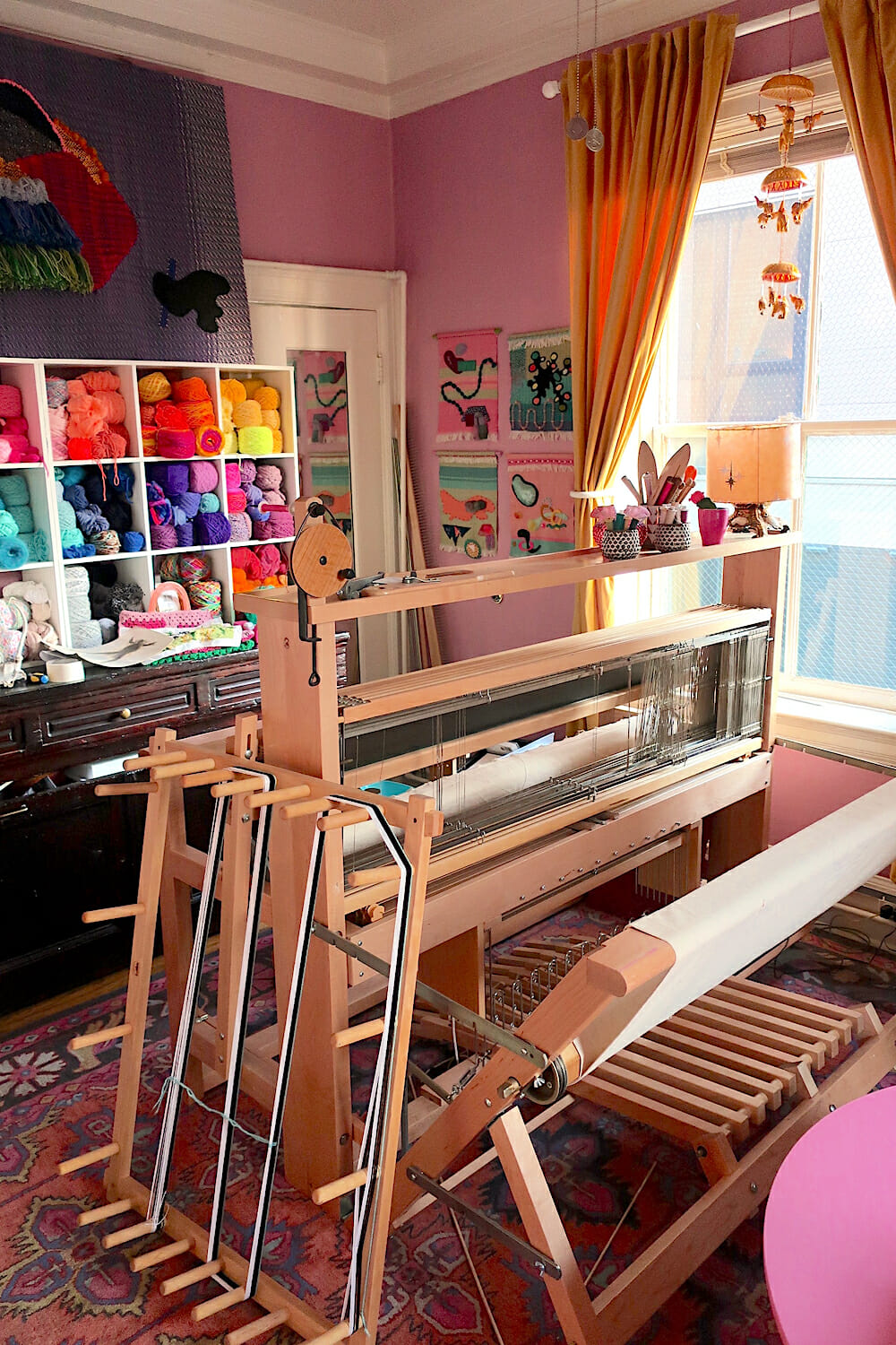 Photo of Kelsey’s loom near a window, in a pink home studio.