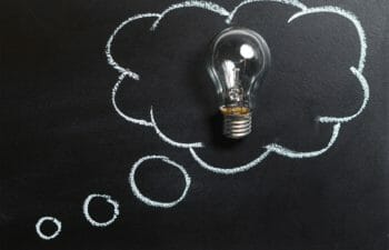 A photo of a lightbulb lying on a chalkboard with a thought bubble drawn around it