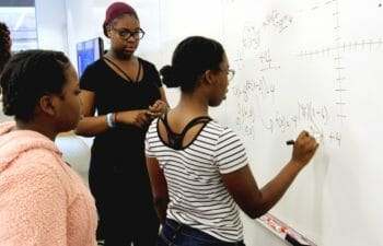 Women solving math on a whiteboard