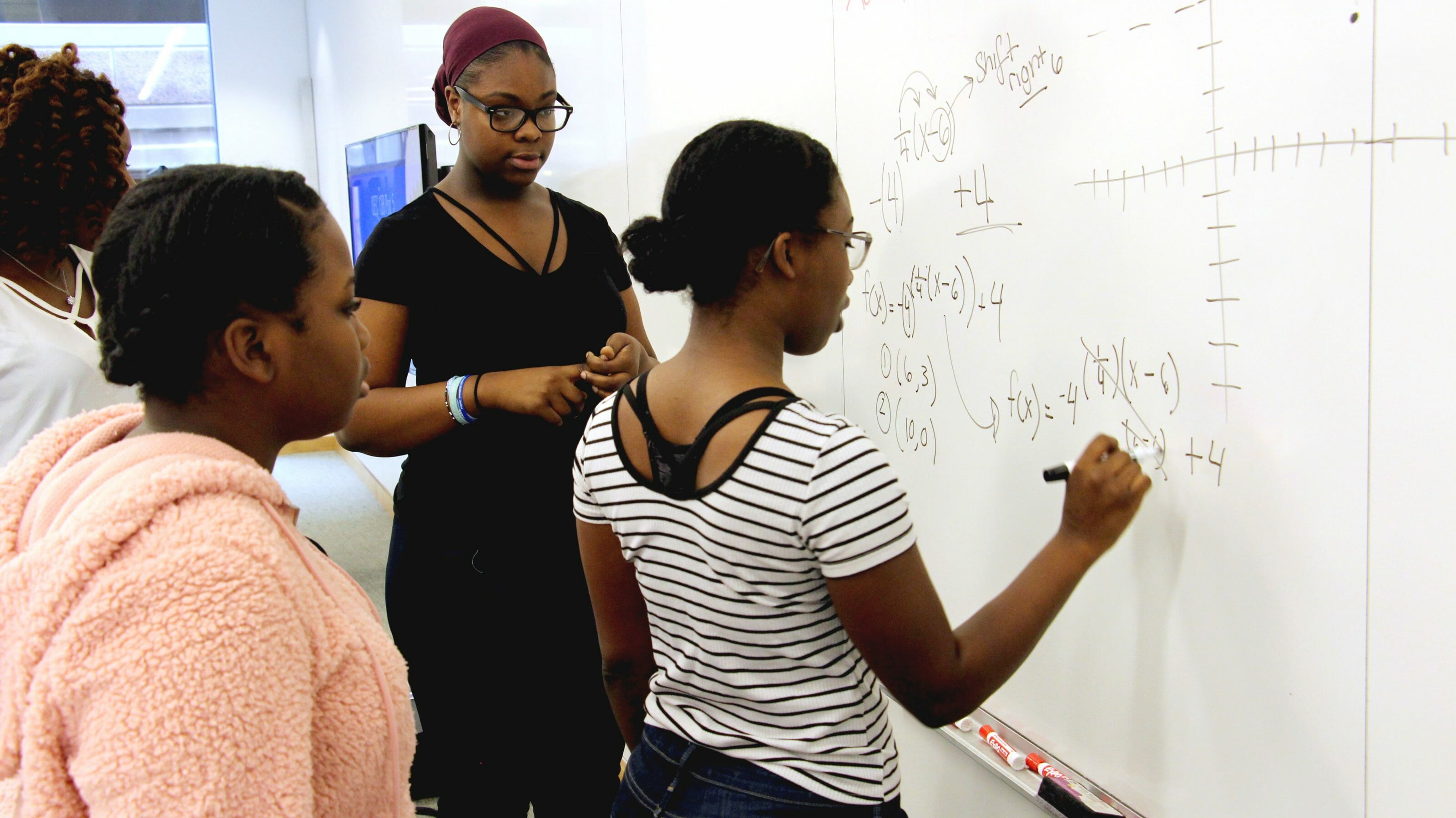 Women solving math on a whiteboard