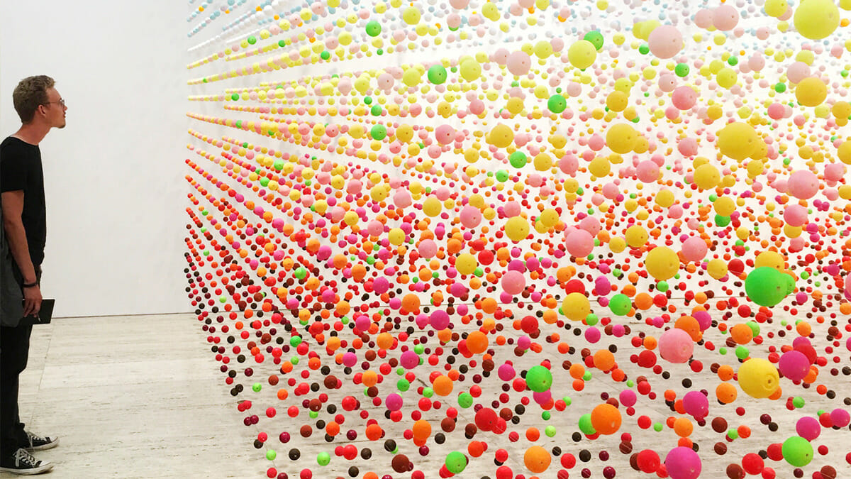 Person looking at a full wall installation of colored balls