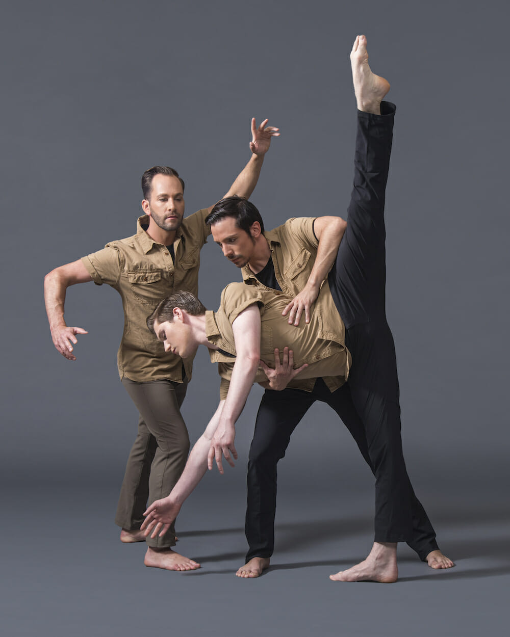 Three male dancers in khaki pose