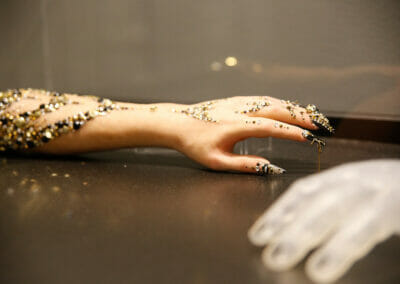 Detail of rhinestone arm artifact with silicone hand covers in the foreground.