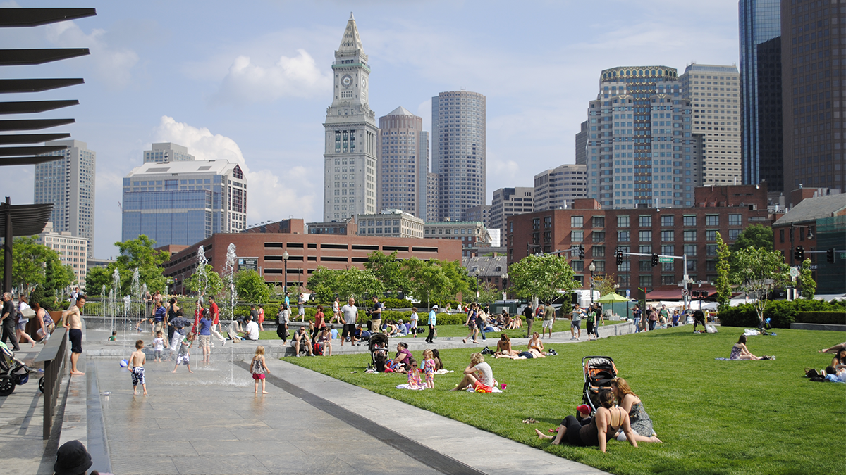Park with city skyline in the background. Adults and children having picnics and playing in the water fountain at the park.(Photo/Rose Fitzgerald Kennedy Greenway Conservancy)
