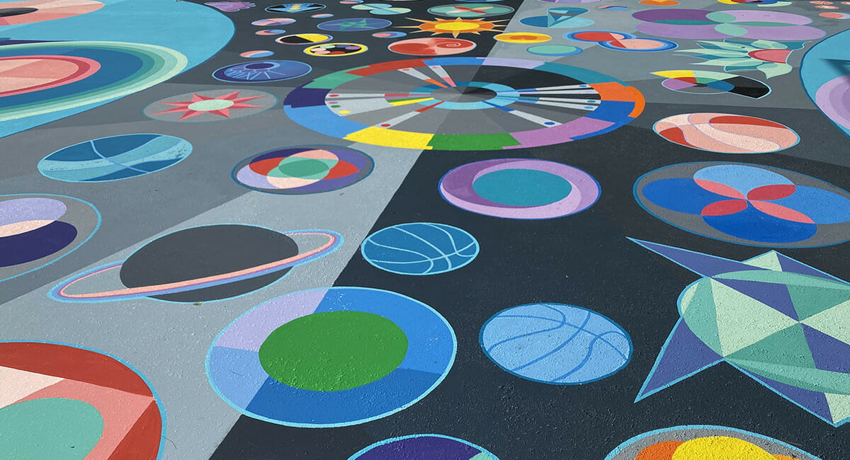 Basketball court painted with various abstract shapes by artist Maria Moteni.