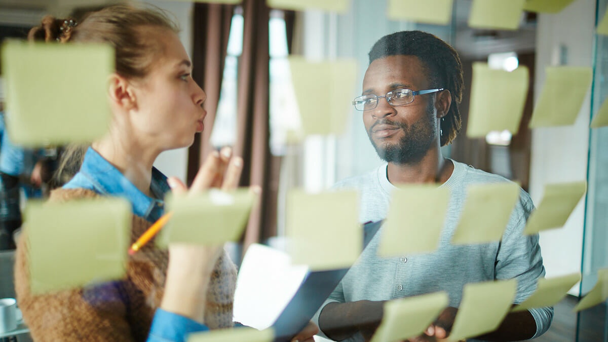 Two adults working on a project with sticky notes organizing their ideas.