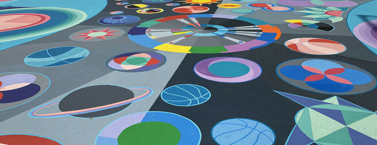 Basketball court painted with various abstract shapes by artist Maria Moteni.