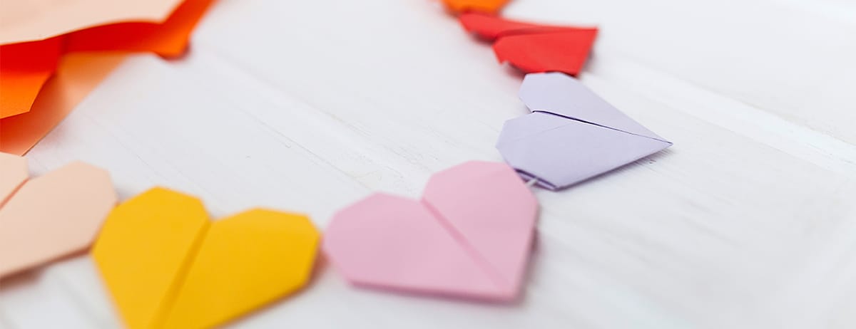 Yellow, pink, and purple paper hearts attached by a string