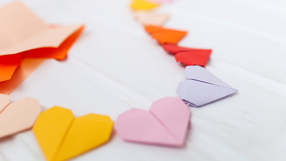 Yellow, pink, purple, and red paper hearts connected by a string